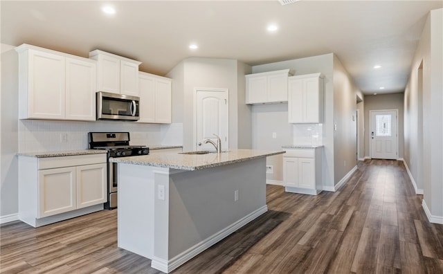 kitchen featuring a kitchen island with sink, appliances with stainless steel finishes, white cabinets, and wood finished floors