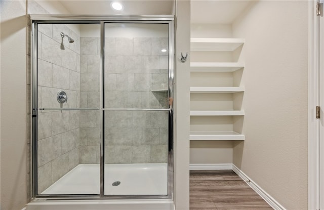 full bathroom with built in features, a stall shower, baseboards, and wood finished floors