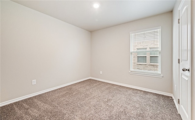 spare room featuring carpet floors and baseboards