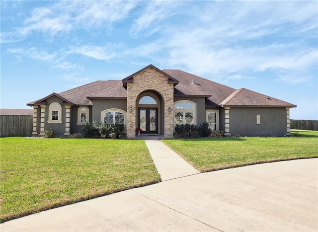 view of front of house with stucco siding, french doors, a front yard, and fence