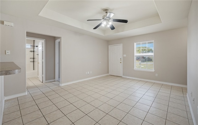 spare room featuring ceiling fan, baseboards, and a tray ceiling