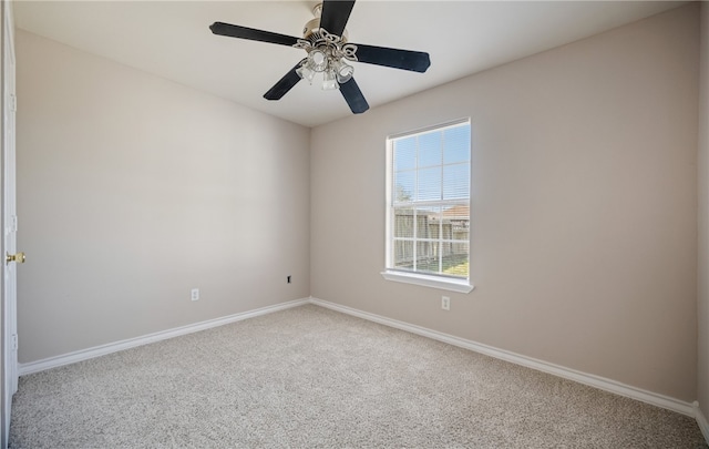 carpeted spare room featuring ceiling fan and baseboards