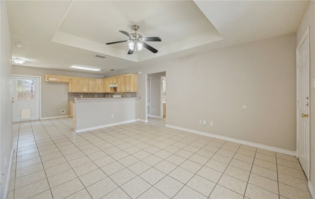 unfurnished living room featuring visible vents, a raised ceiling, baseboards, and ceiling fan