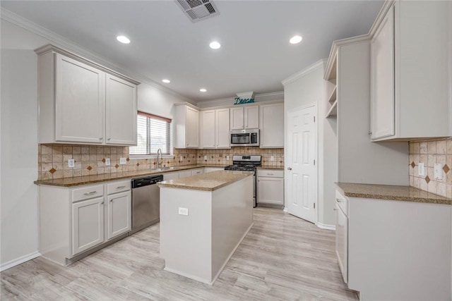 7706 Fort Griffen Dr, Corpus Christi, TX 78414 - kitchen with appliances with stainless steel finishes, decorative backsplash, a center island, light wood-style floors, and ornamental molding