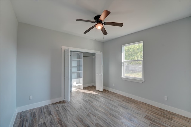 unfurnished bedroom featuring light wood-type flooring, ceiling fan, and a closet