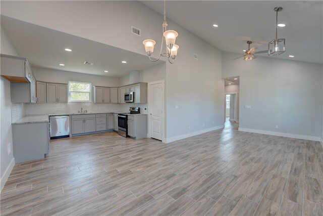 kitchen featuring stainless steel appliances, hanging light fixtures, light hardwood / wood-style floors, and gray cabinetry