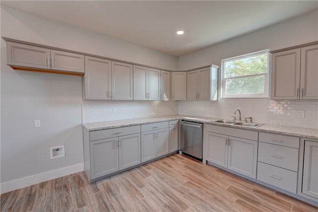 kitchen with light hardwood / wood-style floors, stainless steel dishwasher, sink, and light stone countertops