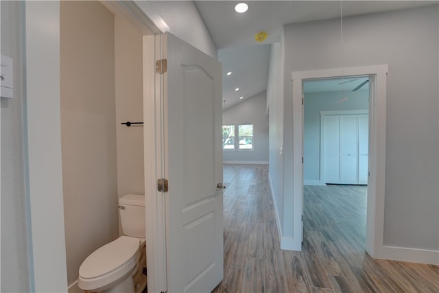 bathroom with wood-type flooring, toilet, and vaulted ceiling