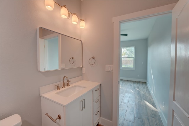 bathroom featuring wood-type flooring, vanity, and toilet