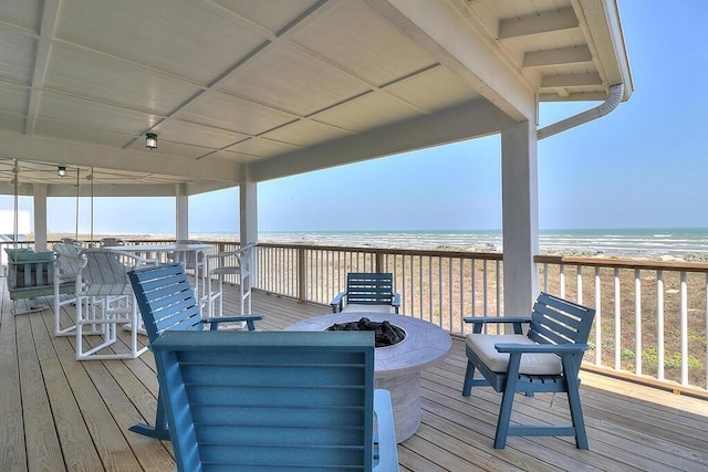 wooden terrace featuring a fire pit, a beach view, and a water view