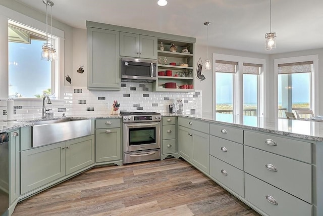 kitchen featuring pendant lighting, sink, light stone counters, and appliances with stainless steel finishes