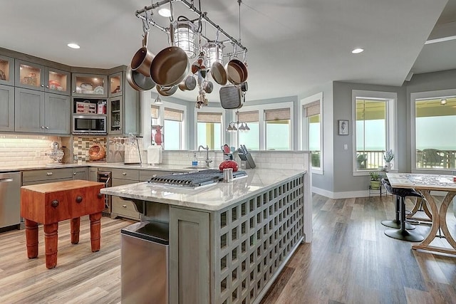 kitchen featuring hanging light fixtures, appliances with stainless steel finishes, sink, and light stone counters