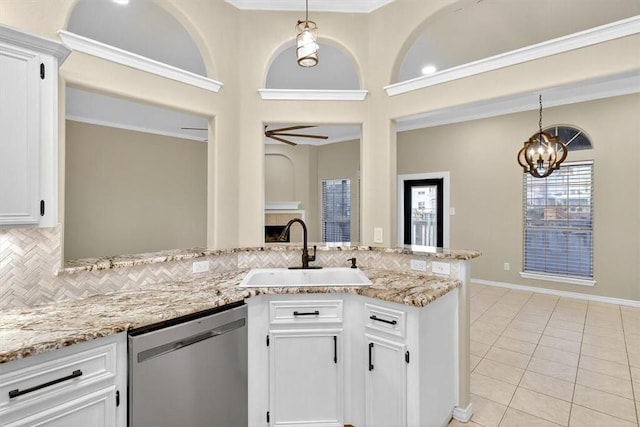 15341 Yardarm Ct, Corpus Christi, TX 78418 - kitchen with stainless steel dishwasher, tasteful backsplash, light tile patterned flooring, white cabinets, and decorative light fixtures