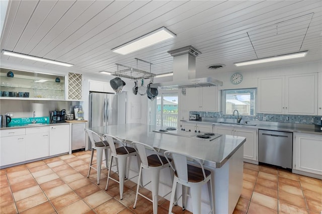 kitchen with island range hood, tasteful backsplash, appliances with stainless steel finishes, and a sink