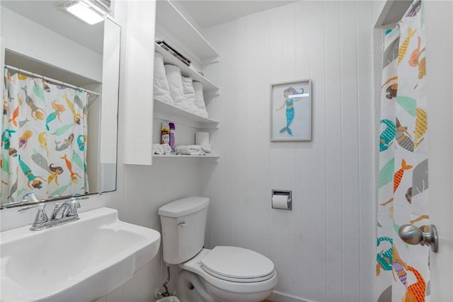 bathroom featuring a sink, toilet, and curtained shower