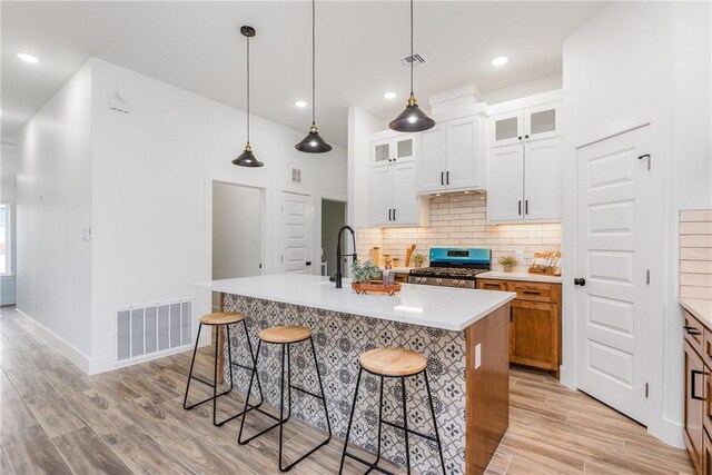2513 Luzius Dr, Corpus Christi, TX 78418 - kitchen with stainless steel range with gas cooktop, a kitchen bar, backsplash, light wood-style flooring, and recessed lighting