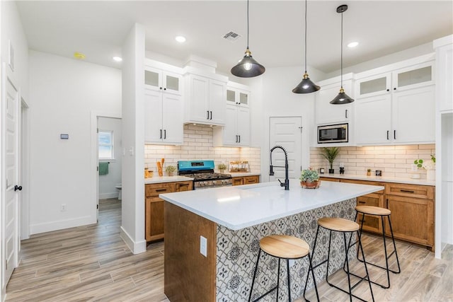 2513 Luzius Dr, Corpus Christi, TX 78418 - kitchen featuring stainless steel appliances, a sink, a breakfast bar area, light wood finished floors, and light countertops