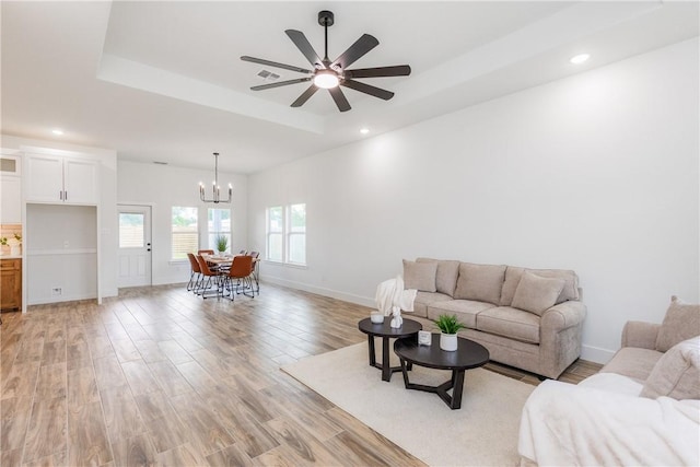 2513 Luzius Dr, Corpus Christi, TX 78418 - living room featuring a chandelier, a tray ceiling, light wood-type flooring, ceiling fan, and baseboards