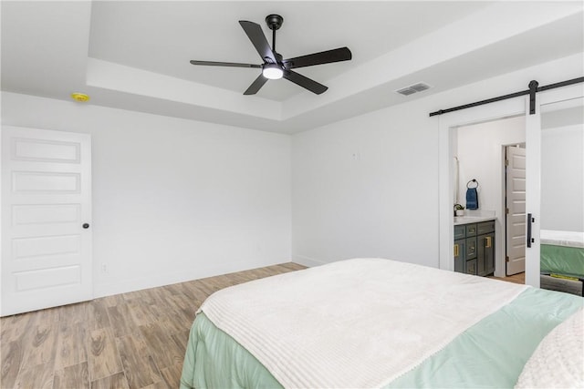 2513 Luzius Dr, Corpus Christi, TX 78418 - bedroom featuring a tray ceiling, a barn door, light wood-style floors, baseboards, and a sink