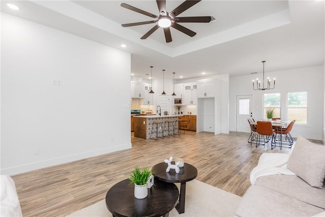 2513 Luzius Dr, Corpus Christi, TX 78418 - living room featuring a chandelier, a tray ceiling, light wood-type flooring, recessed lighting, and ceiling fan