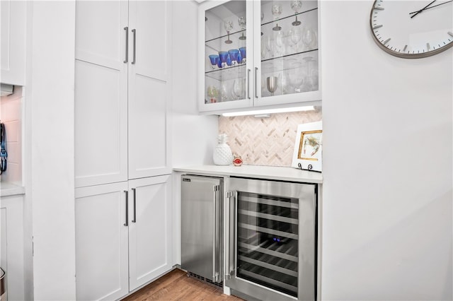 bar featuring white cabinets, wine cooler, tasteful backsplash, light hardwood / wood-style flooring, and stainless steel fridge