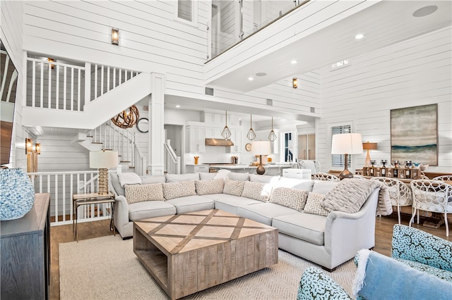 living room featuring wood walls, light hardwood / wood-style floors, and a towering ceiling