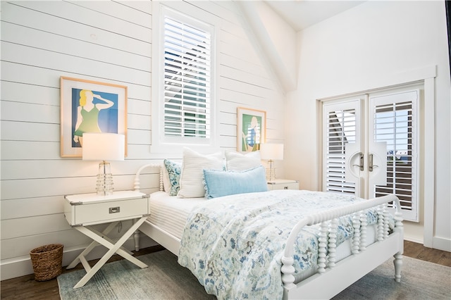 bedroom featuring high vaulted ceiling, wood walls, multiple windows, and dark hardwood / wood-style floors