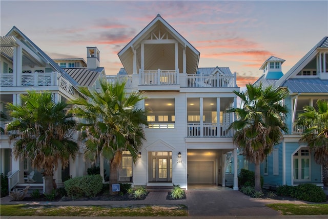 raised beach house featuring a garage and a balcony