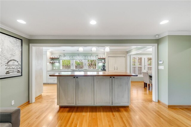 kitchen with light wood-style floors, plenty of natural light, light countertops, crown molding, and baseboards