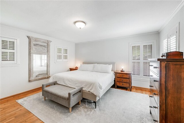 bedroom featuring ornamental molding, light wood finished floors, multiple windows, and baseboards