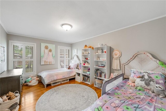 bedroom with ornamental molding and wood finished floors