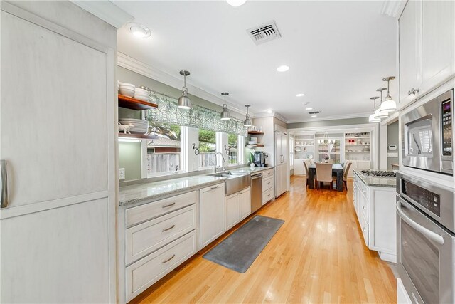 kitchen with stainless steel appliances, open shelves, a sink, light wood finished floors, and white cabinetry