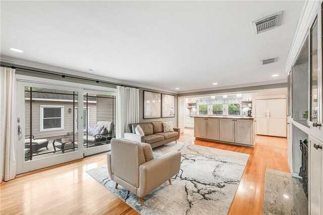living area featuring crown molding, light wood finished floors, and recessed lighting