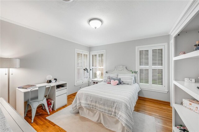bedroom with light wood finished floors, ornamental molding, and baseboards