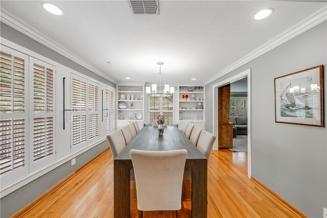 dining area with a chandelier, light wood finished floors, crown molding, built in features, and recessed lighting