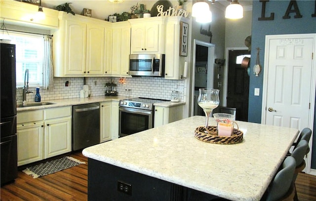 kitchen with hanging light fixtures, a center island, appliances with stainless steel finishes, and sink