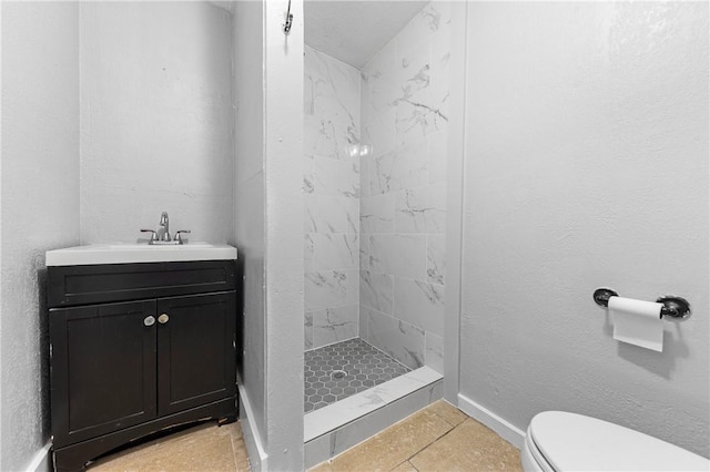 bathroom with tiled shower, tile patterned floors, vanity, and toilet