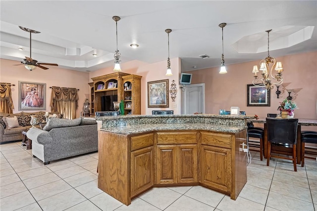 kitchen featuring light tile patterned flooring, a kitchen island, pendant lighting, and a tray ceiling