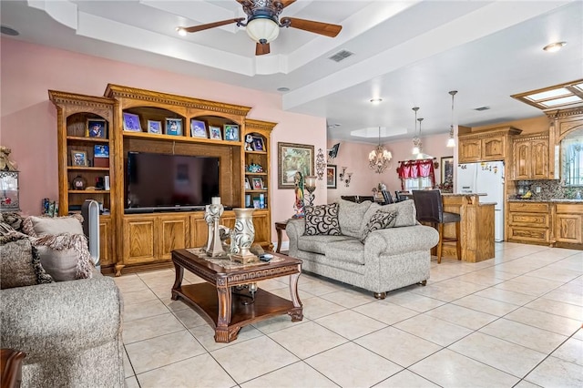 tiled living room with a raised ceiling and ceiling fan