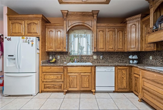 kitchen featuring light tile patterned flooring, sink, dark stone countertops, white appliances, and decorative backsplash