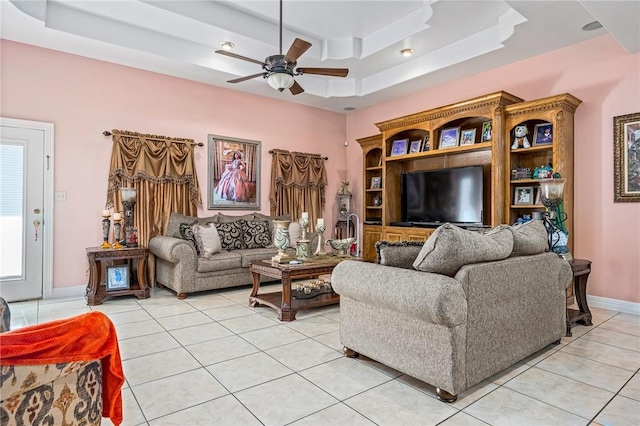 living room with light tile patterned flooring, ceiling fan, and a tray ceiling