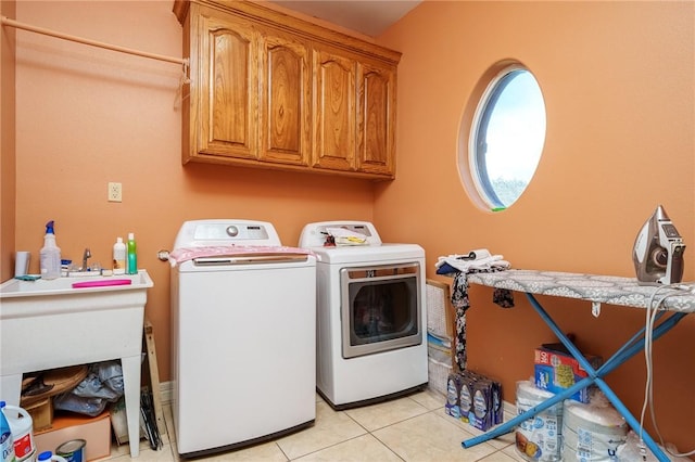 laundry room with cabinets, light tile patterned floors, and washer and clothes dryer