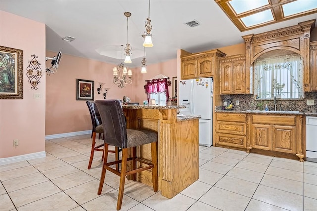 kitchen with sink, a kitchen bar, a center island, light tile patterned floors, and white appliances