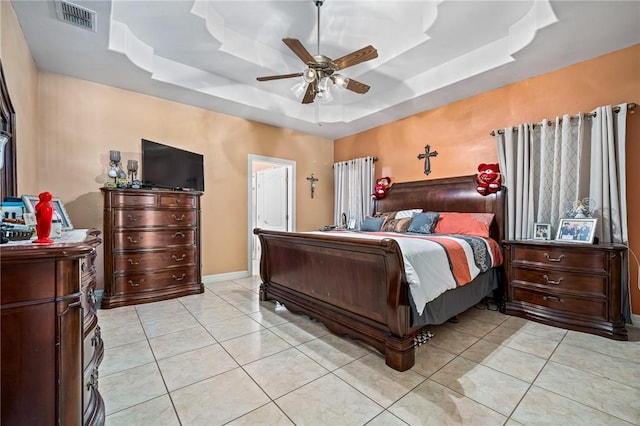 tiled bedroom with a tray ceiling and ceiling fan