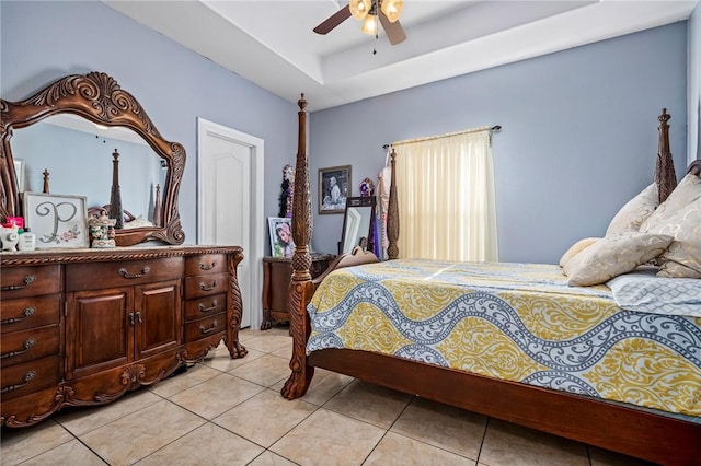 bedroom with ceiling fan, a raised ceiling, and light tile patterned floors