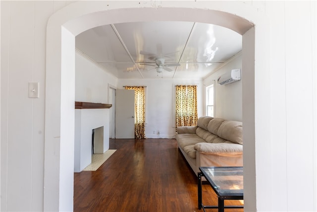 living room featuring dark hardwood / wood-style flooring, a wall unit AC, ceiling fan, and crown molding