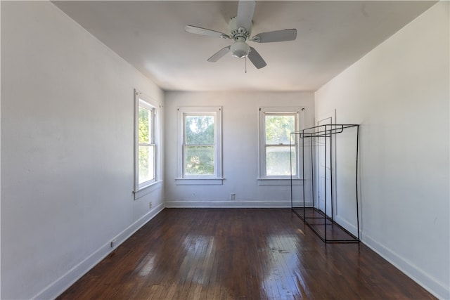 empty room with ceiling fan, plenty of natural light, and dark hardwood / wood-style flooring