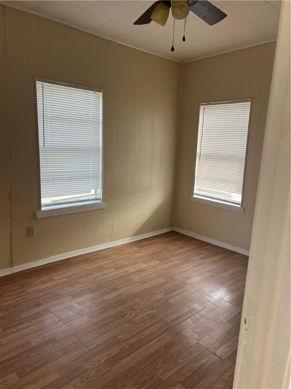 spare room with ceiling fan, plenty of natural light, and wood-type flooring