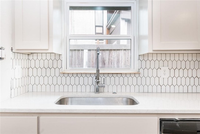 kitchen featuring tasteful backsplash, light stone countertops, sink, and white cabinets