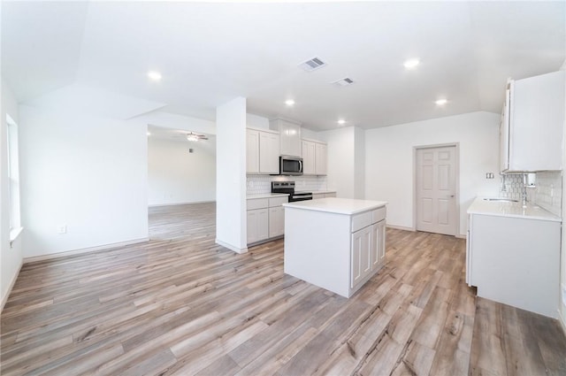 kitchen featuring white cabinetry, appliances with stainless steel finishes, light hardwood / wood-style floors, and a kitchen island